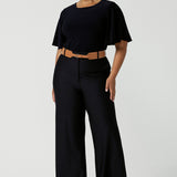 A good full length trouser for plus size women, these Navy blue, tailored wide leg pants are shown on a size 18, curvy woman. Worn with a high neck, flutter sleeve top in navy jersey, these elegant pants wear for work as smart casual wear. Shop made in Australia trousers for women online at women's clothing brand Leina & Fleur.