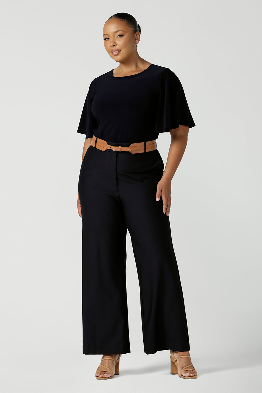 A good full length trouser for plus size women, these Navy blue, tailored wide leg pants are shown on a size 18, curvy woman. Worn with a high neck, flutter sleeve top in navy jersey, these elegant pants wear for work as smart casual wear. Shop made in Australia trousers for women online at women's clothing brand Leina & Fleur.