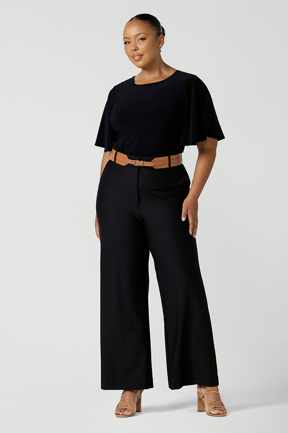 A plus size 18 woman wears a casual jersey top in navy blue, styled with navy tailored pants. This Australian-made women's top has flutter sleeves, a high, round neckline and and high-low hem perfect for weekend casual and travel capsule wardrobes.
