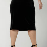 Back view of a Woman wears the Brooke Skirt in Black Velour. Slim fit tube skirt for evening wear. Flattering style. Size inclusive fashion Australian made size 8 - 24. Styled back with black high heel and cowl neck gold Chrissy Top.
