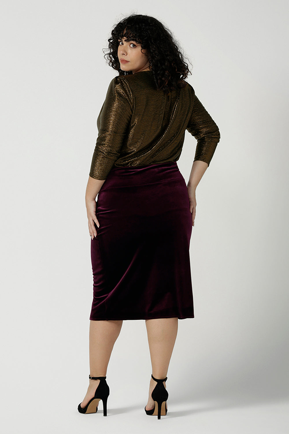 Back view of a s size 18 woA size 18 woman wears the Brooke velour skirt in Wine Velour. A fitted tube skirt in velour knee length. Styled back with Chrissy top in Bullion xanadu. Made in Australia for plus to petite women size 8 - 24.
