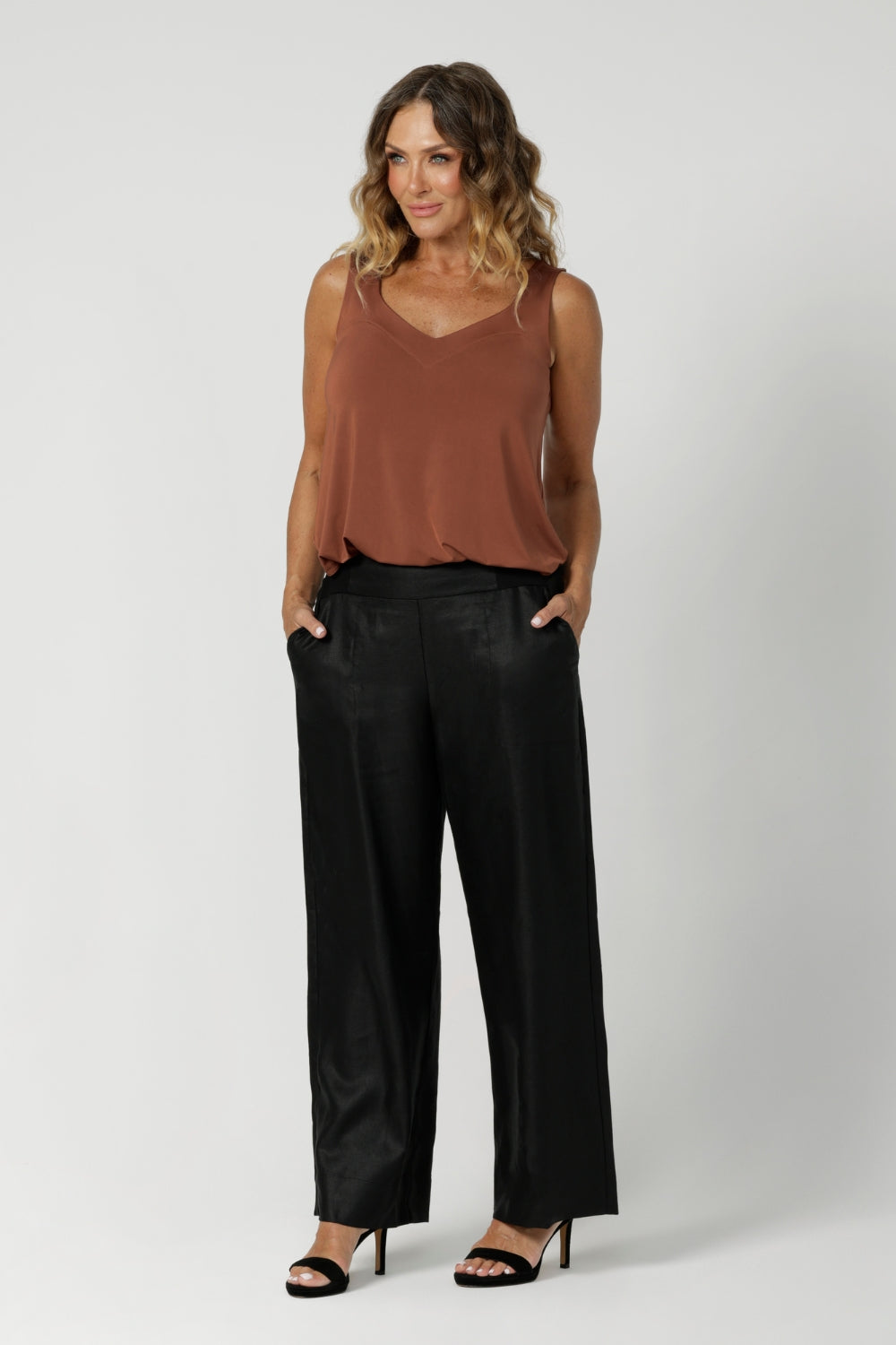 Over 40's model wears black back-to-work pant featuring a perfect blend of comfort and style for the office or any professional setting. Designed in a pull-on, mid-rise style, they offer an easy, seamless fit. The waistband features a bamboo jersey panel at the back, providing extra comfort around the waist and tummy area, ensuring a soft, flexible feel throughout the day.