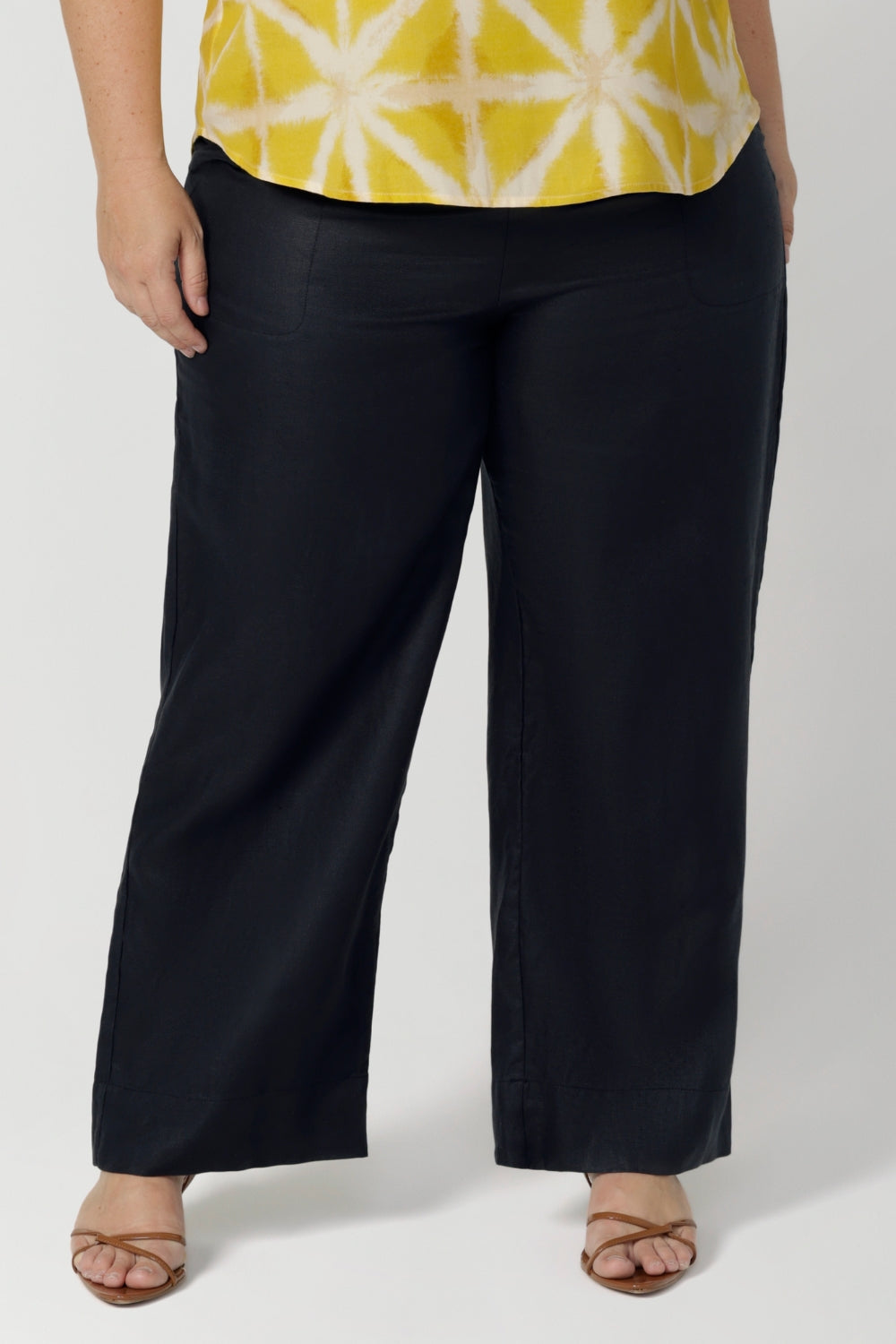 Plus sized woman wears full-length linen pants, worn with yellow workwear shirt, These linen pants can be worn for work, casual outings and can be dressed up for  more polished occasions. The deep navy shade brings a rich, versatile hue, easily pairing with a range of tops and jackets for a chic timeless style year round.