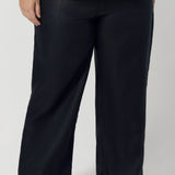 Plus sized woman wears full-length linen pants, worn with yellow workwear shirt, These linen pants can be worn for work, casual outings and can be dressed up for  more polished occasions. The deep navy shade brings a rich, versatile hue, easily pairing with a range of tops and jackets for a chic timeless style year round.