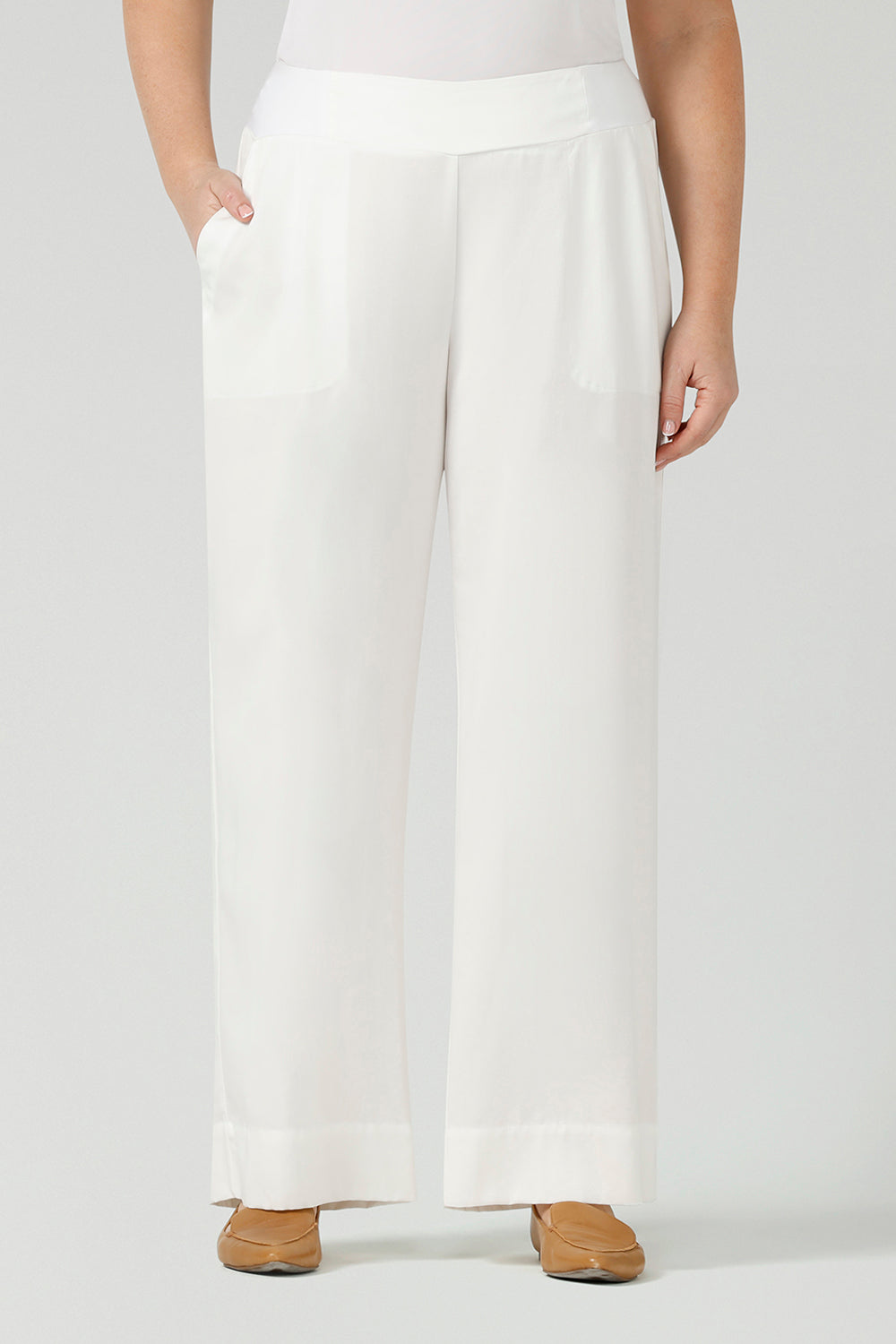 Close up of a curvy size, size 12 woman wearing wide leg pants with pockets. These pull-on, easy care pants are comfortable for your everyday workwear capsule wardrobe. Shop these Australian-made wide leg trousers online in sizes 8 to 24, petite to plus sizes.