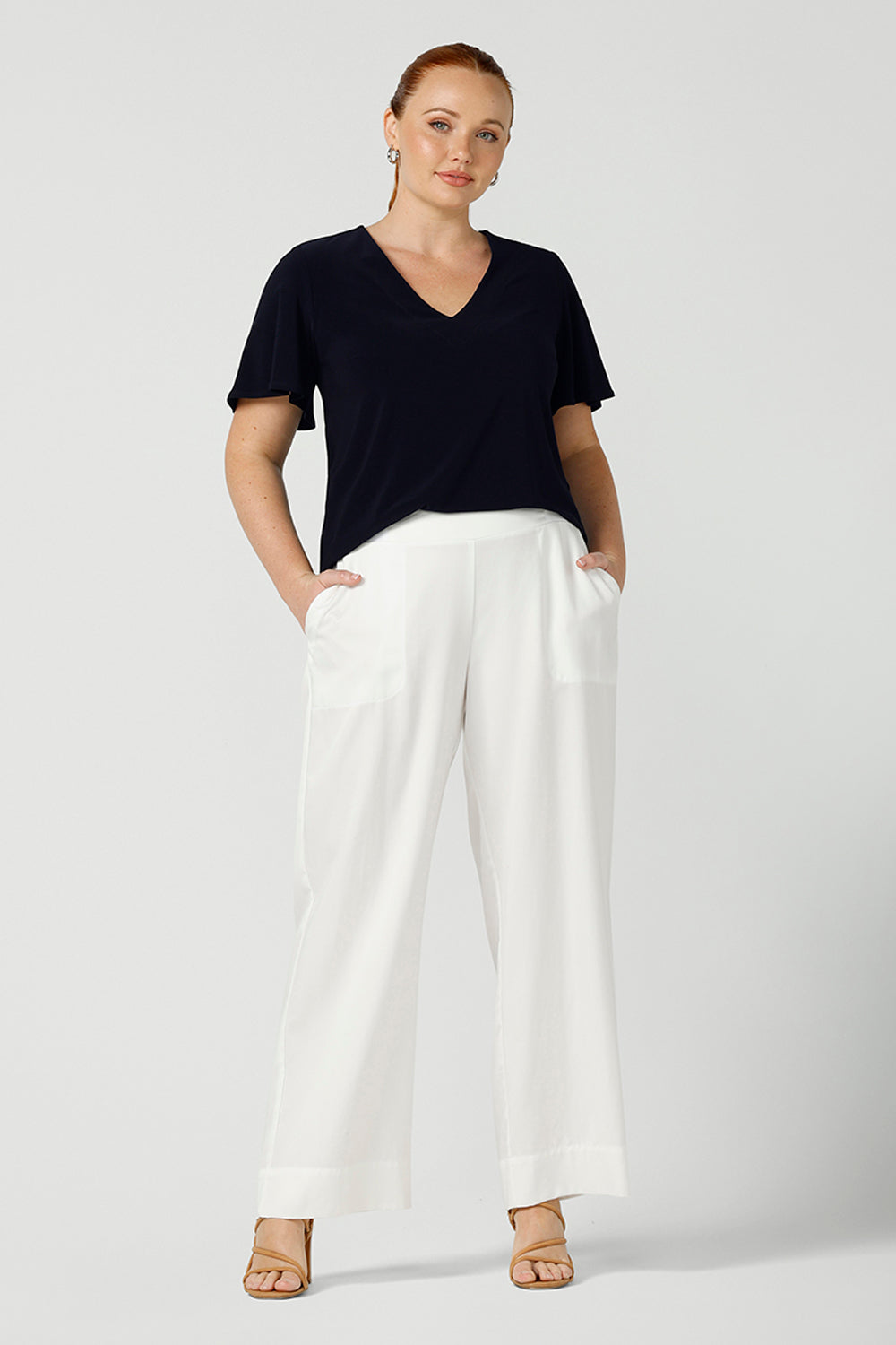 A curvy size, size 12 woman wears wide leg pants with pockets with a navy top. These pull-on, easy care pants are comfortable for your everyday workwear capsule wardrobe. Shop these Australian-made wide leg trousers online in sizes 8 to 24, petite to plus sizes.