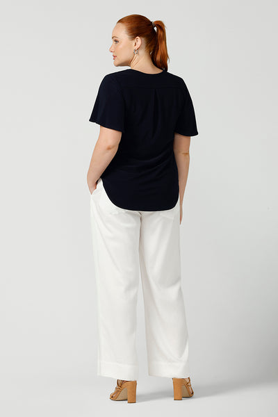 Back view of curvy size, size 12 woman wearing wide leg pants with pockets with a navy top. These pull-on, easy care pants are comfortable for your everyday workwear capsule wardrobe. Shop these Australian-made wide leg trousers online in sizes 8 to 24, petite to plus sizes.