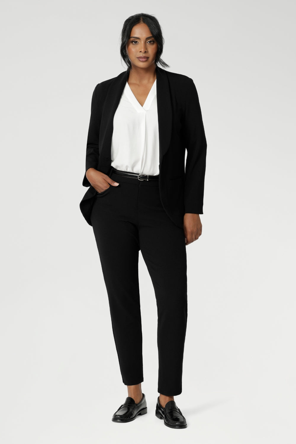 Image of a 40-year-old woman wearing work wear pants in Black Scuba Crepe. This easy care pant is made of scuba crepe fabric and gives a luxe stretch feel. Comfortable off duty pants are made in Australia for women sized 8-24. Pants are photographed with matching black blazer for a full suit look.