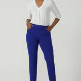 A size 10 woman wears the Corbin Pant in Cobalt, a high waist pant with belt loops and cropped leg length. Made in Australia for women size 8-24. Comfortable cocktail suiting work suit look for corporate women. Size inclusive petite to plus size fashion 8-24. 