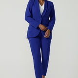 A size 10 woman wears the Corbin Pant in Cobalt, a high waist pant with belt loops and cropped leg length. Made in Australia for women size 8-24. Comfortable cocktail suiting work suit look for corporate women. Size inclusive petite to plus size fashion 8-24. Styled back with the Merit Blazer in Cobalt.