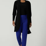 A size 10 woman wears the Bardon Duster in Black, a jersey cardigan with balloon sleeves and made in comfortable jersey. Petite to plus size and styled back with the Corbin Pant in Cobalt blue. Made in Australia for women size 8-24. 