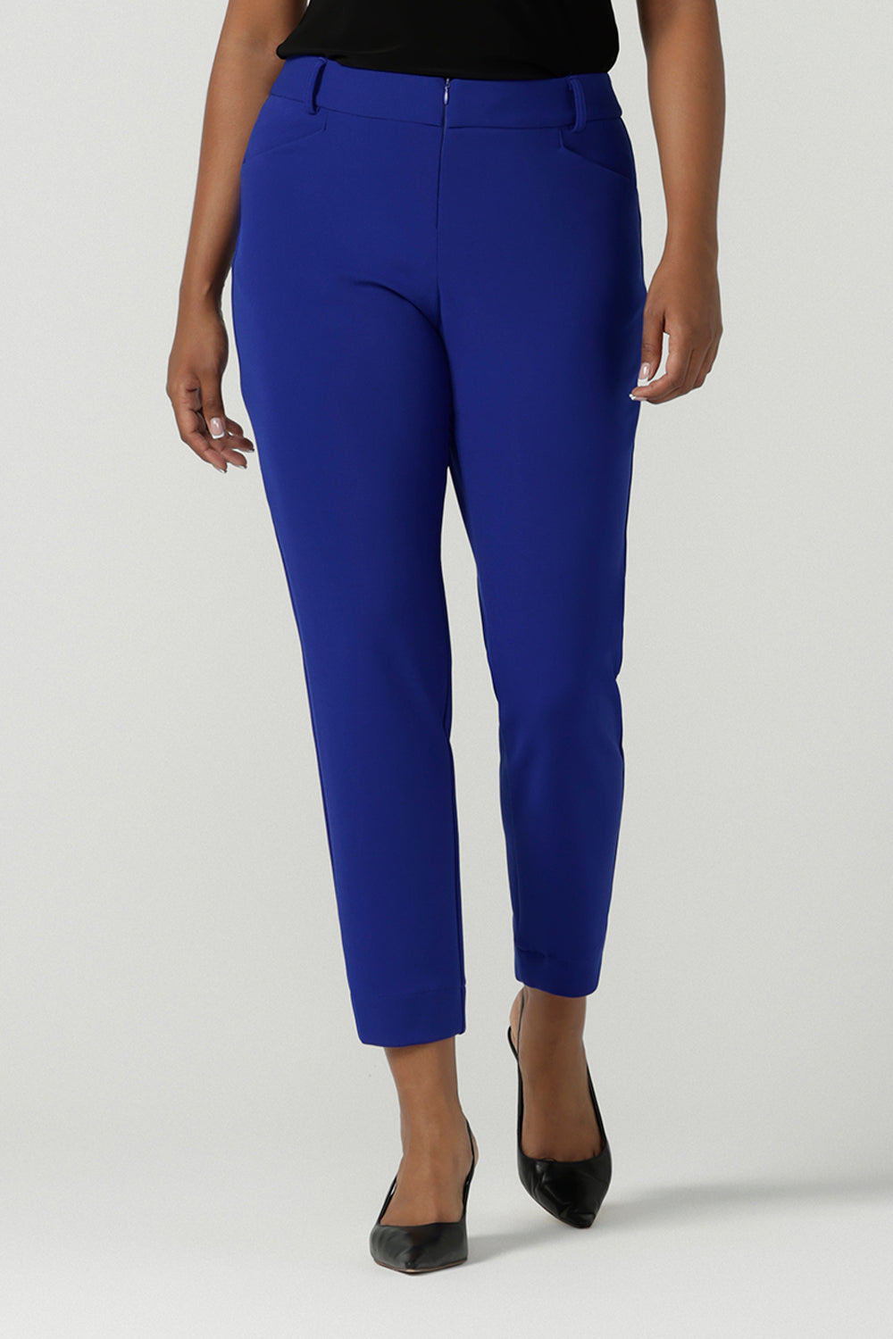 A size 10 woman wears the Corbin Pant in Cobalt, a high waist pant with belt loops and cropped leg length. Made in Australia for women size 8-24. Comfortable cocktail suiting work suit look for corporate women. Size inclusive petite to plus size fashion 8-24. 