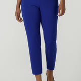 A size 10 woman wears the Corbin Pant in Cobalt, a high waist pant with belt loops and cropped leg length. Made in Australia for women size 8-24. Comfortable cocktail suiting work suit look for corporate women. Size inclusive petite to plus size fashion 8-24. 