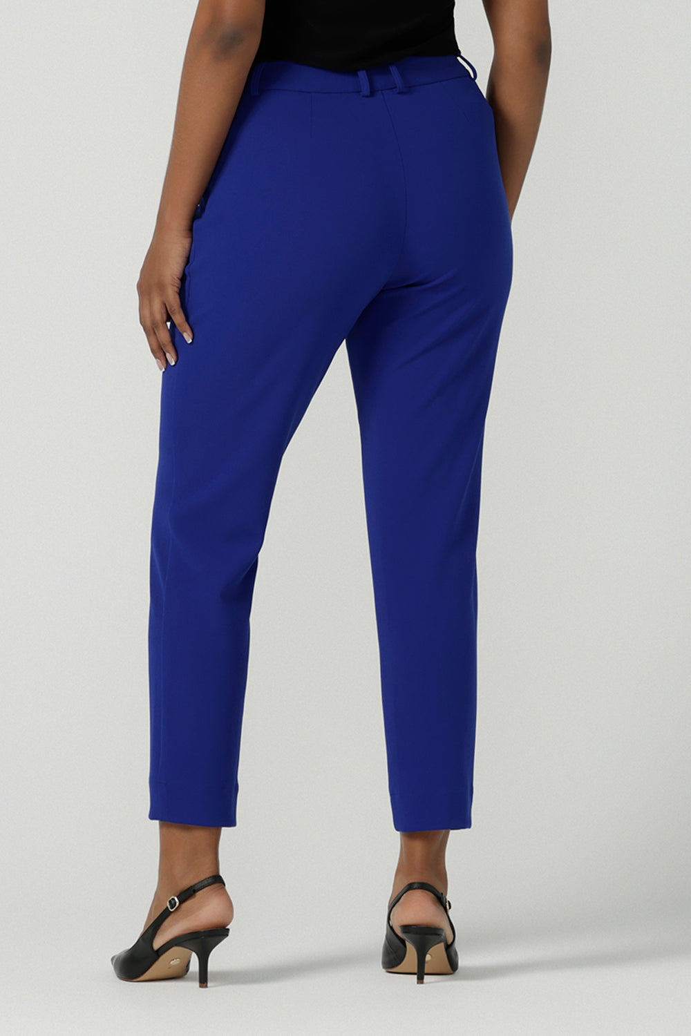 Back view of a size 10 woman wears the Corbin Pant in Cobalt, a high waist pant with belt loops and cropped leg length. Made in Australia for women size 8-24. Comfortable cocktail suiting work suit look for corporate women. Size inclusive petite to plus size fashion 8-24.