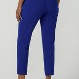 Back view of a size 10 woman wears the Corbin Pant in Cobalt, a high waist pant with belt loops and cropped leg length. Made in Australia for women size 8-24. Comfortable cocktail suiting work suit look for corporate women. Size inclusive petite to plus size fashion 8-24.