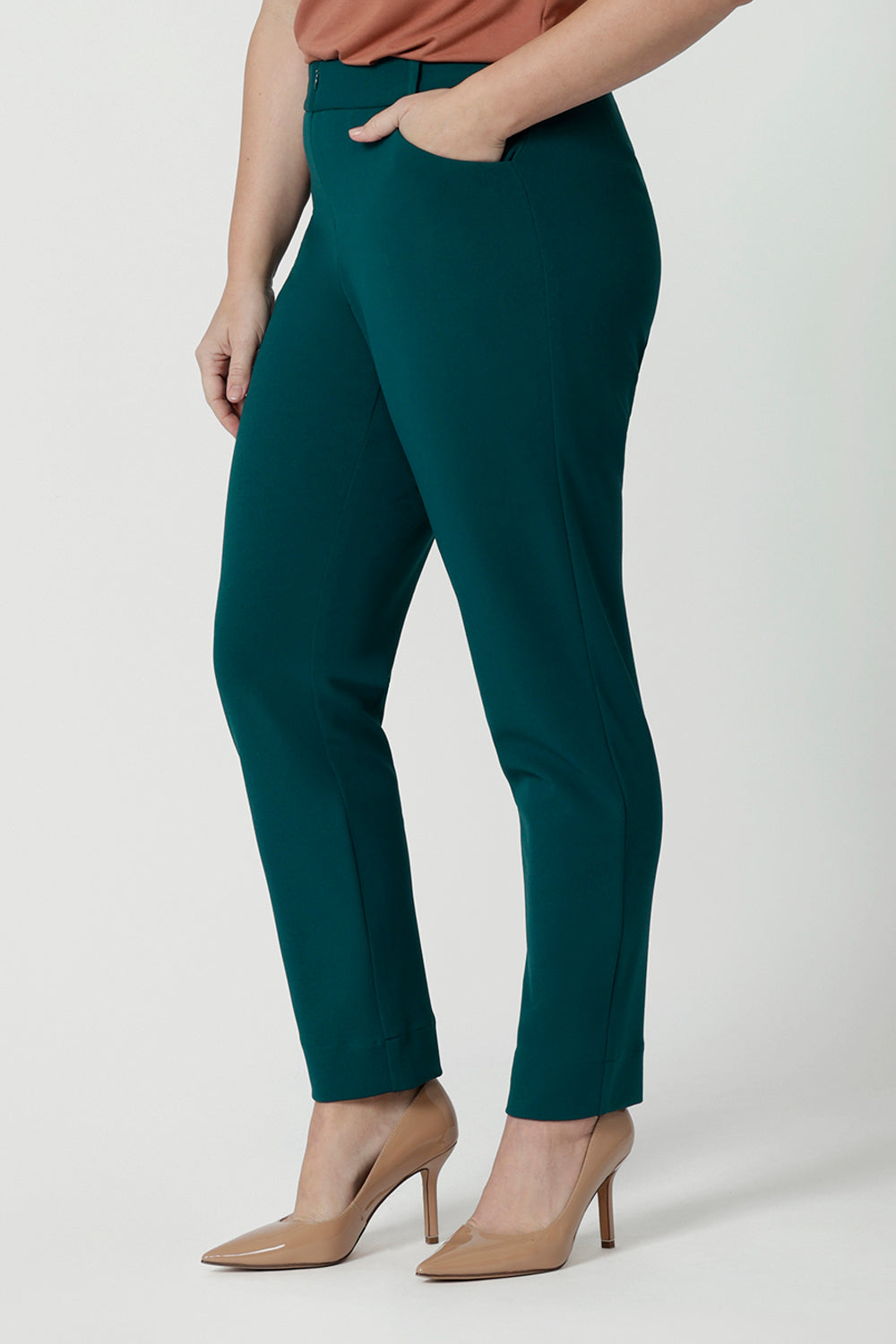 Side view of good workwear trousers for petite height women. A size 12 woman wears a tapered leg, green work pant. Good pants for work, these trousers are made from stretchy jersey and are comfortable for all-day wear. Made in Australia by Australian and New Zealand women's clothes label, Leina & Fleur, shop easy-care workwear for petite to plus size women. 