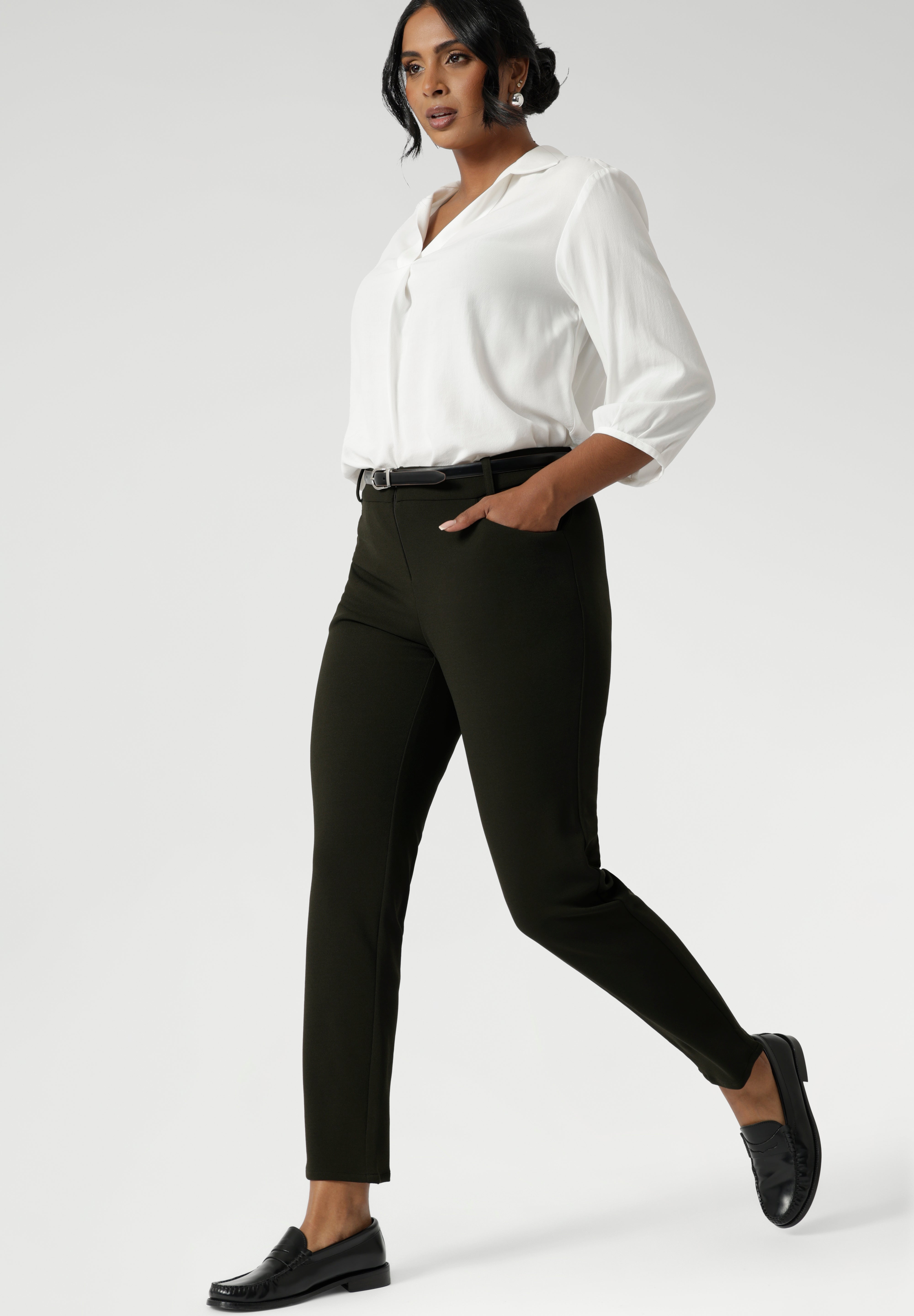 The pants are designed with angled front pockets, giving them a modern touch, while the back darts ensure a tailored fit that contours to the shape of the body. Size 10 woman wears her Corbin Pants with lightweight blouse and black loafers.