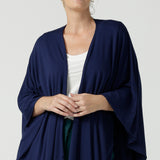 Woman wears the cove poncho in bamboo. Made in Australia for women size 8 - 24. Heat regulating bamboo. Travel friendly. One size fits all. French Navy bamboo colour. 