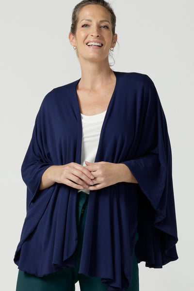 Woman wears the cove poncho in bamboo. Made in Australia for women size 8 - 24. Heat regulating bamboo. Travel friendly. One size fits all. French Navy bamboo colour. 