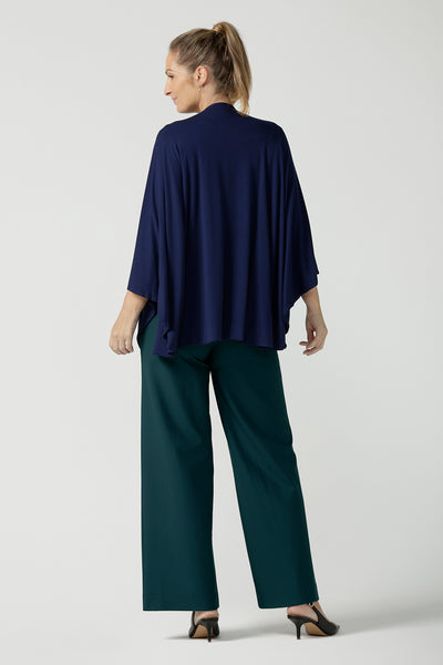 Back view of a woman wearing the cove poncho in bamboo. Made in Australia for women size 8 - 24. Heat regulating bamboo. Travel friendly. One size fits all. French Navy bamboo colour.