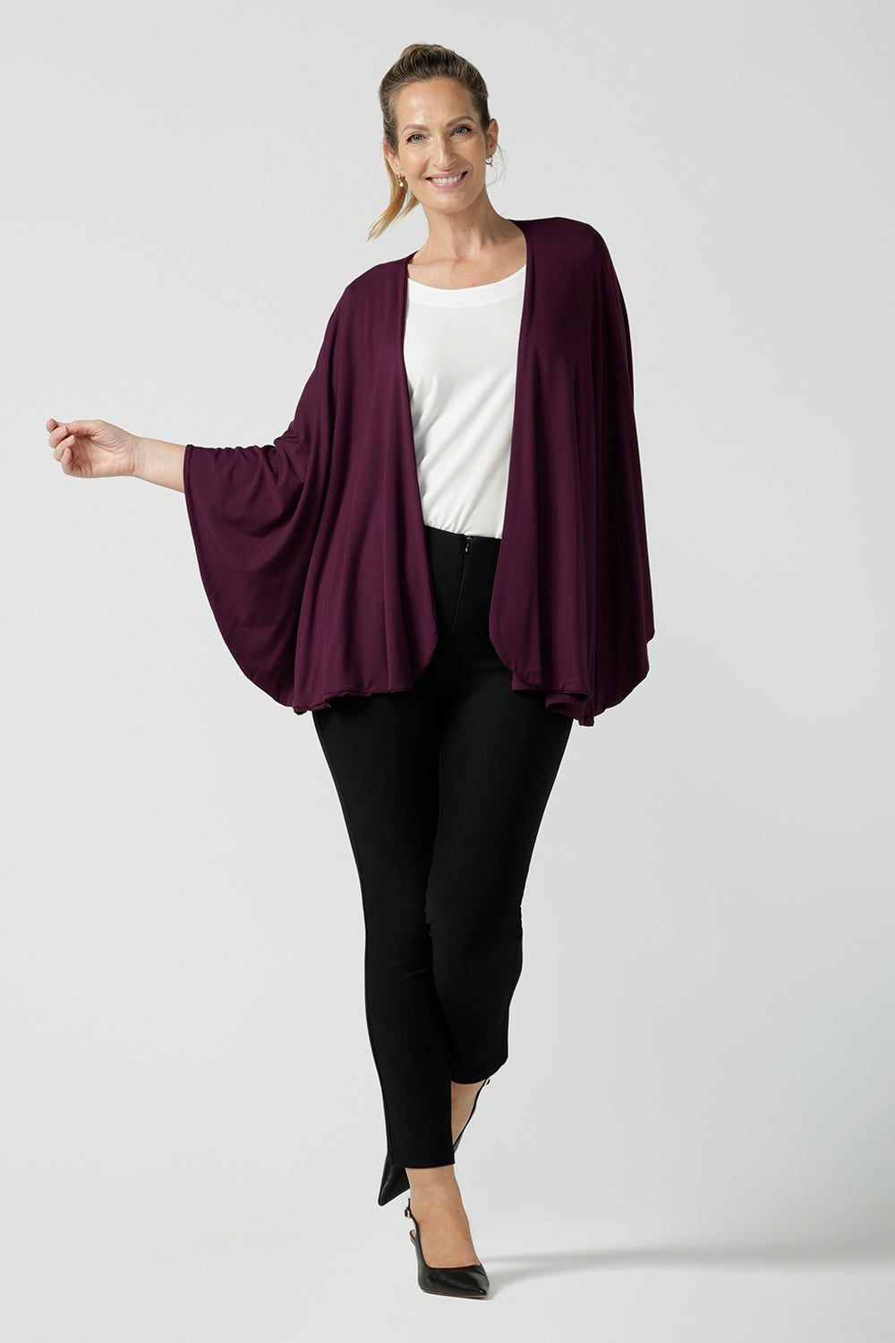 A size 10 woman wears a Bamboo Cove poncho wrap. Soft weighted bamboo that is a versatile work to travel and weekend piece. Made in Australia for women size 8 - 24. 