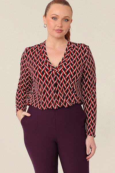 A long sleeve, women's work top, this red, white and black chevron print V-neck top has a shirttail hem. Worn by a curvy woman,  shop this office top at Australian fashion brand, L&F in petite to plus sizes.