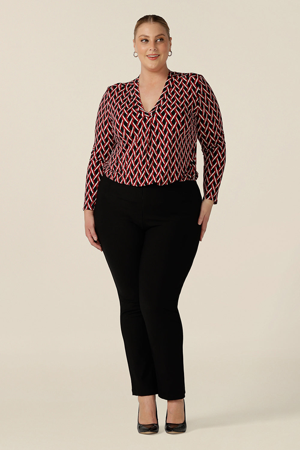 A long sleeve ladies work top, this red, white and black chevron print V-neck top has a shirttail hem. Worn with slim leg black pants for work, by a plus size, size 18 woman,  shop this office top at Australian fashion brand, L&f in sizes 8 to 24.