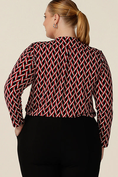 Back view of a  long sleeve ladies work top, this red, white and black chevron print V-neck top has a shirttail hem. Worn by a plus size, size 18 woman,  shop this office top at Australian fashion brand, L&f in sizes 8 to 24.