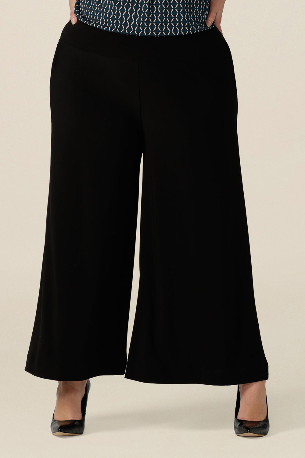 Comfortable, black wide leg pants with pockets are shown in a size 18. These pull-on, easy care pants are comfortable for your everyday workwear capsule wardrobe. Shop these black pants online in sizes 8 to 24, petite to plus sizes.