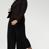 Plus size woman wears black culottes with black turtle neck & brown jacket. Stretch black pants for women, have a smooth waistband, side pockets and are a pull-on style. Made in Australia, from dry touch jersey fabric in sizes 8-24.