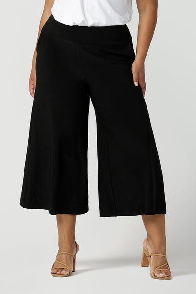 Close up of a size 18, plus size woman wearing black wide-leg pants and a V-neck white bamboo jersey top with short sleeves.  Cropped in length, these black culottes have a smooth waistband, side pockets and are pull-on pants made in stretch jersey. Made in Australia, the pants are size inclusive in sizes 8 to sizes 24.