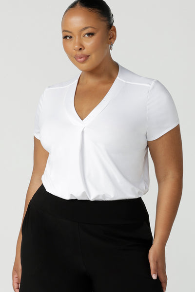 A size 18, plus size size woman wears a short sleeve, V neck top in white bamboo jersey. A great top for plus size women, the tailored pleat below the V neckline flatters curves. Shop tops made in Australia at women's clothing brand, Leina & Fleur.