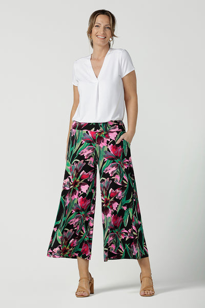 A size 10, 40 plus woman wears printed jersey, wide leg pants with a V-neck, short sleeve top in white bamboo jersey. Pull-on pants with a deep waistband, the cropped, culotte legs make great summer pants that work for petite heights as well as taller women. Shop pants online in sizes 8 to 24.