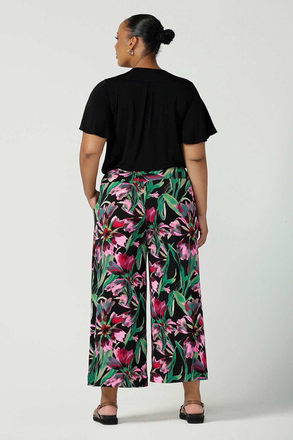 Back view of a plus size, size 18 woman wearing printed jersey, wide leg pants with a V-neck, flutter sleeve top in black bamboo jersey. Pull-on pants with a deep waistband, the cropped, culotte legs make great summer pants that work for petite heights as well as taller women.