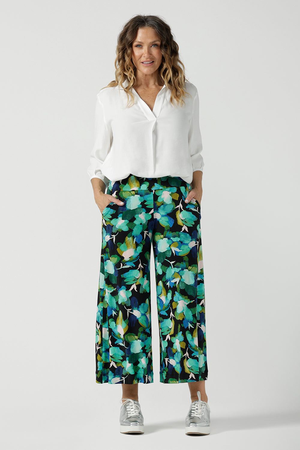 Size 12 woman wears the Dany culotte in Canopy, a wide leg culotte with the canopy print. A bold green colour splatter print. Styled back with nude heels and a white shirt. Made in Australia for women size 8 - 24. 