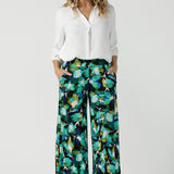 Size 12 woman wears the Dany culotte in Canopy, a wide leg culotte with the canopy print. A bold green colour splatter print. Styled back with nude heels and a white shirt. Made in Australia for women size 8 - 24. 