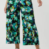 Size 12 woman wears the Dany culotte in Canopy, a wide leg culotte with the canopy print. A bold green colour splatter print. Styled back with nude heels and a white shirt. Made in Australia for women size 8 - 24. 