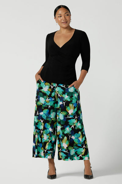 A size 10 woman wears the Dany culotte in Canopy, a full leg culotte with a canopy print. A bold green colour splatter print. Styled back with pink heels and a navy wrap top. Made in Australia for women size 8 - 24.