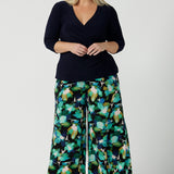 Size 18 woman wears the Dany culotte in Canopy, a full leg culotte with a canopy print. A bold green colour splatter print. Styled back with pink heels and a navy wrap top. Made in Australia for women size 8 - 24. 