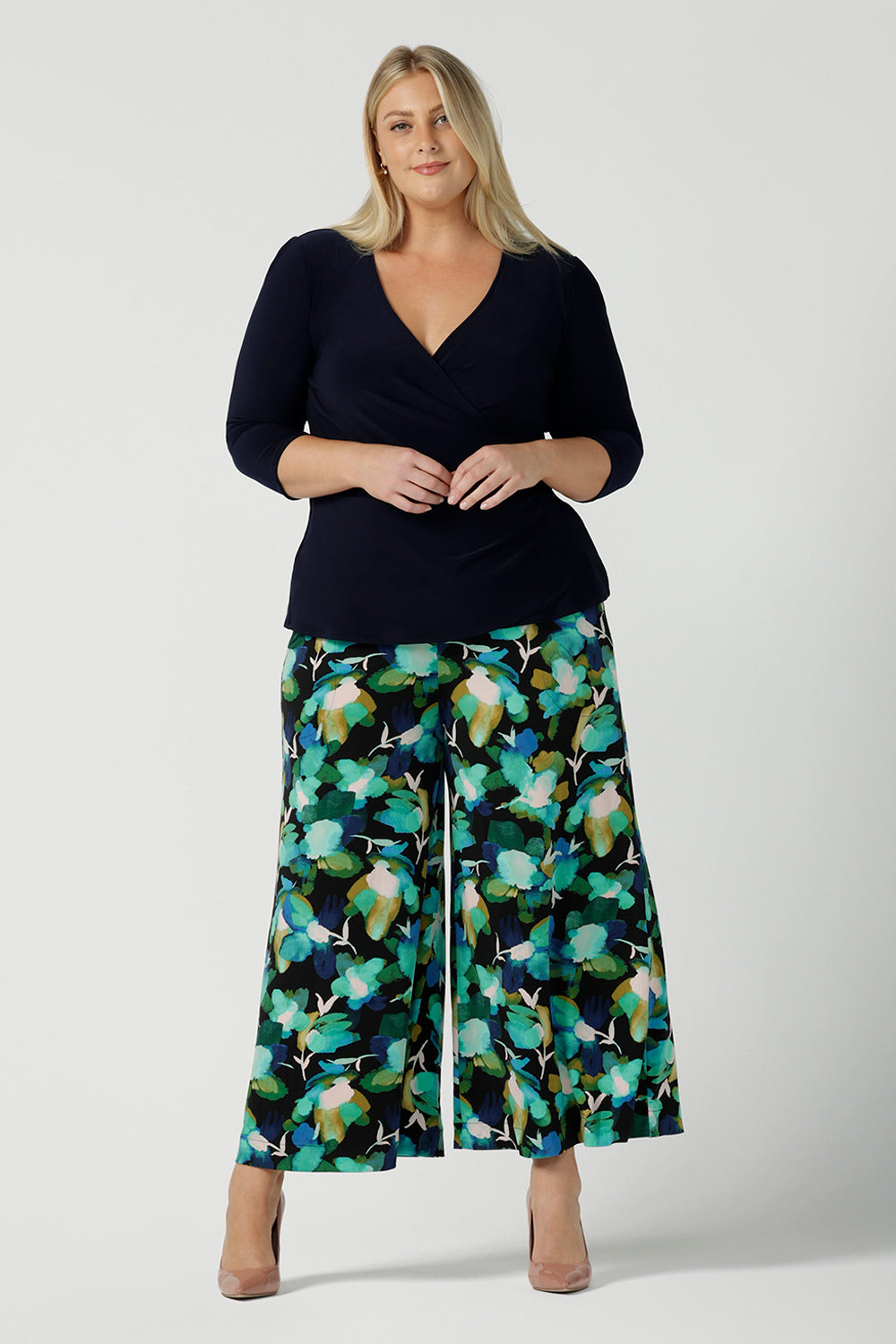 Size 18 woman wears the Dany culotte in Canopy, a full leg culotte with a canopy print. A bold green colour splatter print. Styled back with pink heels and a navy wrap top. Made in Australia for women size 8 - 24. 