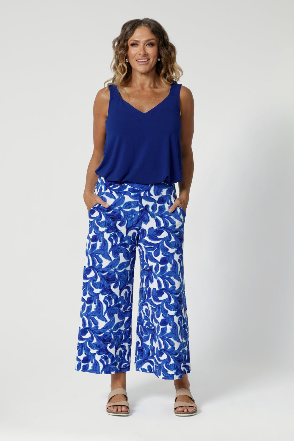 Over 40's woman wears wide leg culottes with matching cobalt coloured cami, paired with neutral sandals for summer ready look. Clothing Brand Leina & Fleur stock these printed pants in sizes 8-24.