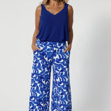 Over 40's woman wears wide leg culottes with matching cobalt coloured cami, paired with neutral sandals for summer ready look. Clothing Brand Leina & Fleur stock these printed pants in sizes 8-24.