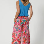 Over 40's woman wears bamboo cami in opal shade, paired back with brightly printed pants, creating a summer ready casual look paired with some flat travel shoes. Cami is stocked in sizes 8-24.