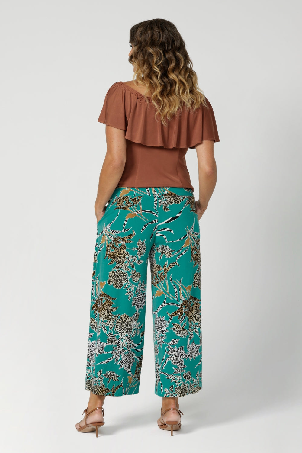 Back view of printed culotte pants worn by sizes 12 woman paired with clay coloured top. These Leina & Fleur Dany Pants are a highly sought-after style that combines comfort, versatility, and a flattering fit for all heights. Providing full-body stretch, flattering silhouette and all-day comfort for back to work and weekend events. Available in size 8-24.