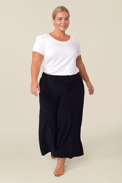 Good pants for petite women, a curvy, size 16 woman wears black culotte pants by Australian fashion brand, Leina & Fleur. Cropped trousers with a stretchy, pull on waistband, these easy-care wide leg pants are worn with a short sleeve top in white bamboo jersey. Shop wide leg pants online in petite to plus sizes.