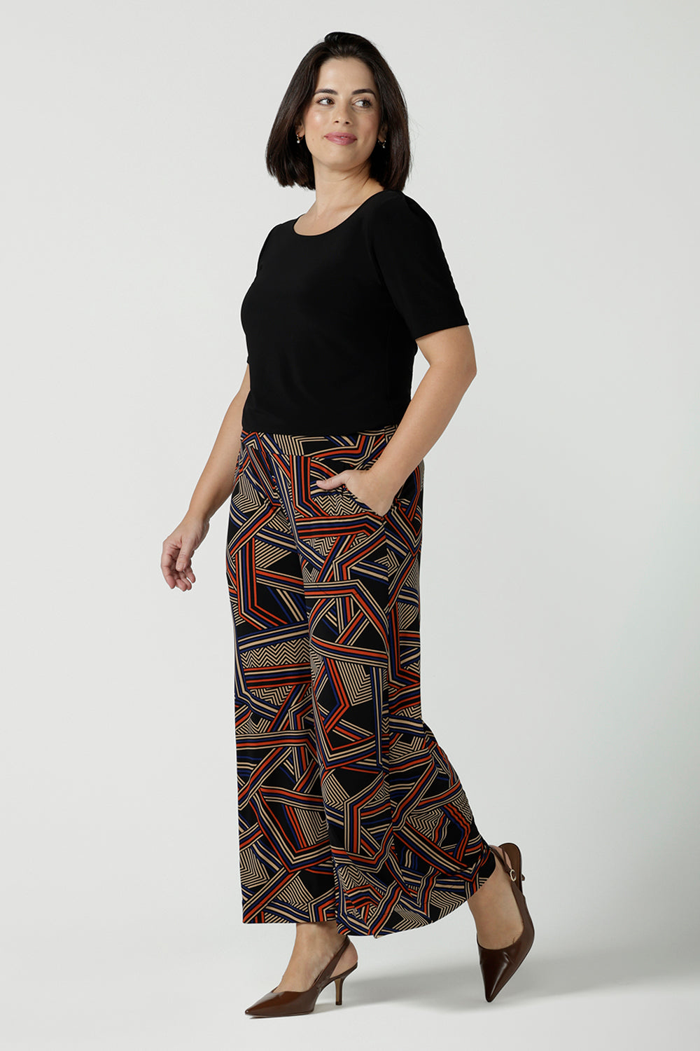 A size 10 woman wears the Dany Culotte in Trixie, a printed Jersey work pant with a geometric pattern. Wide leg with functional pockets and wide waistband. Cropped length and petite height friendly. Made in Australia for women size 8 - 24.