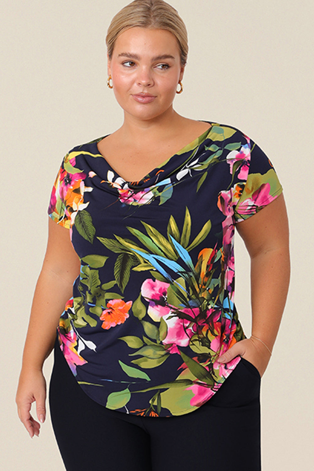 A size 14 curvy woman wears a cowl neck short sleeve jersey top in a floral print. She wears the top. Designed and made in Australia for petite to plus size women.