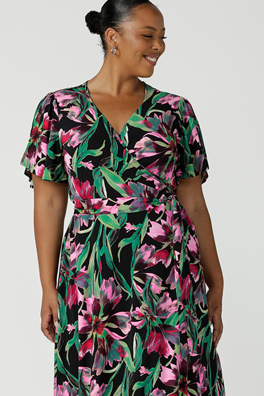 Close up of the dress bodice of a floral print jersey wrap dress with flutter sleeves worn by a size 18 plus size woman. A good wrap dress for summer, shop Australian-made plus size wrap dresses online at Australian fashion brand Leina & Fleur.