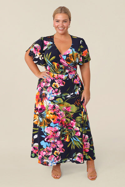 A petite height size 14 woman, wearing a chic dress for plus size and fuller figure women, this V-neck dress with flutter sleeves comes in a floral print and has a midi-length skirt, this dress is good for casual weekend wear.