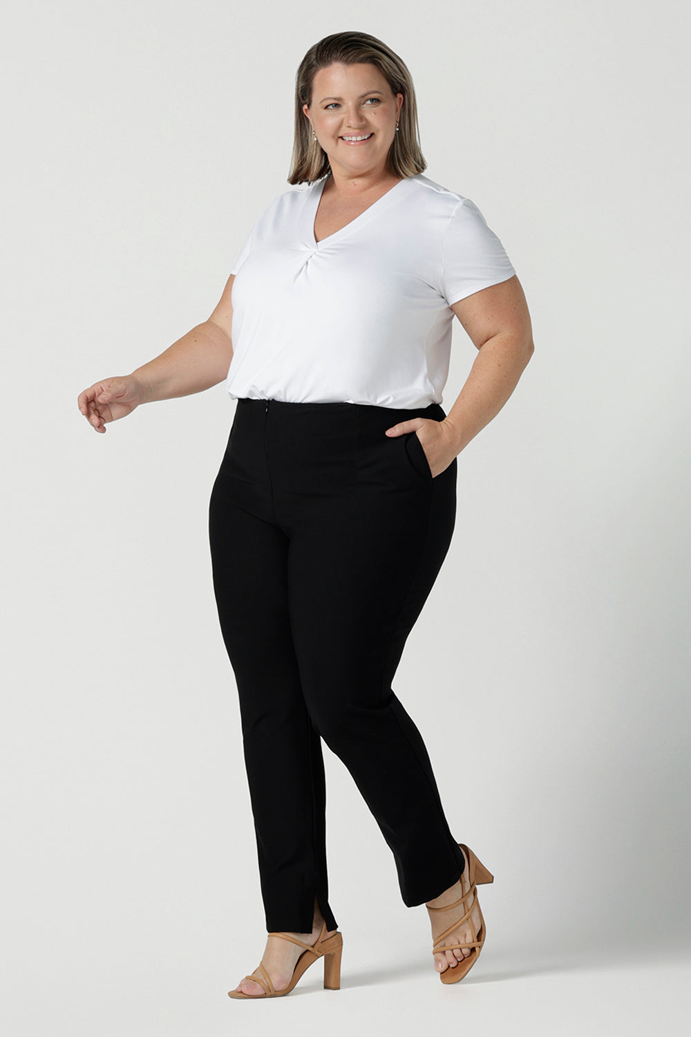 A plus size, size 18 woman wears slim leg, black pants by Australian and New Zealand women's clothing brand, L&F. These comfortable work pants are worn with a white Emily top in bamboo. Made in Australia for women size 8 - 24.